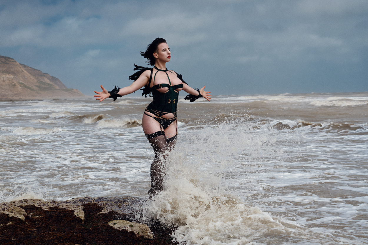 elettra arazatah in black atelier bordelle lingerie in front of the sea