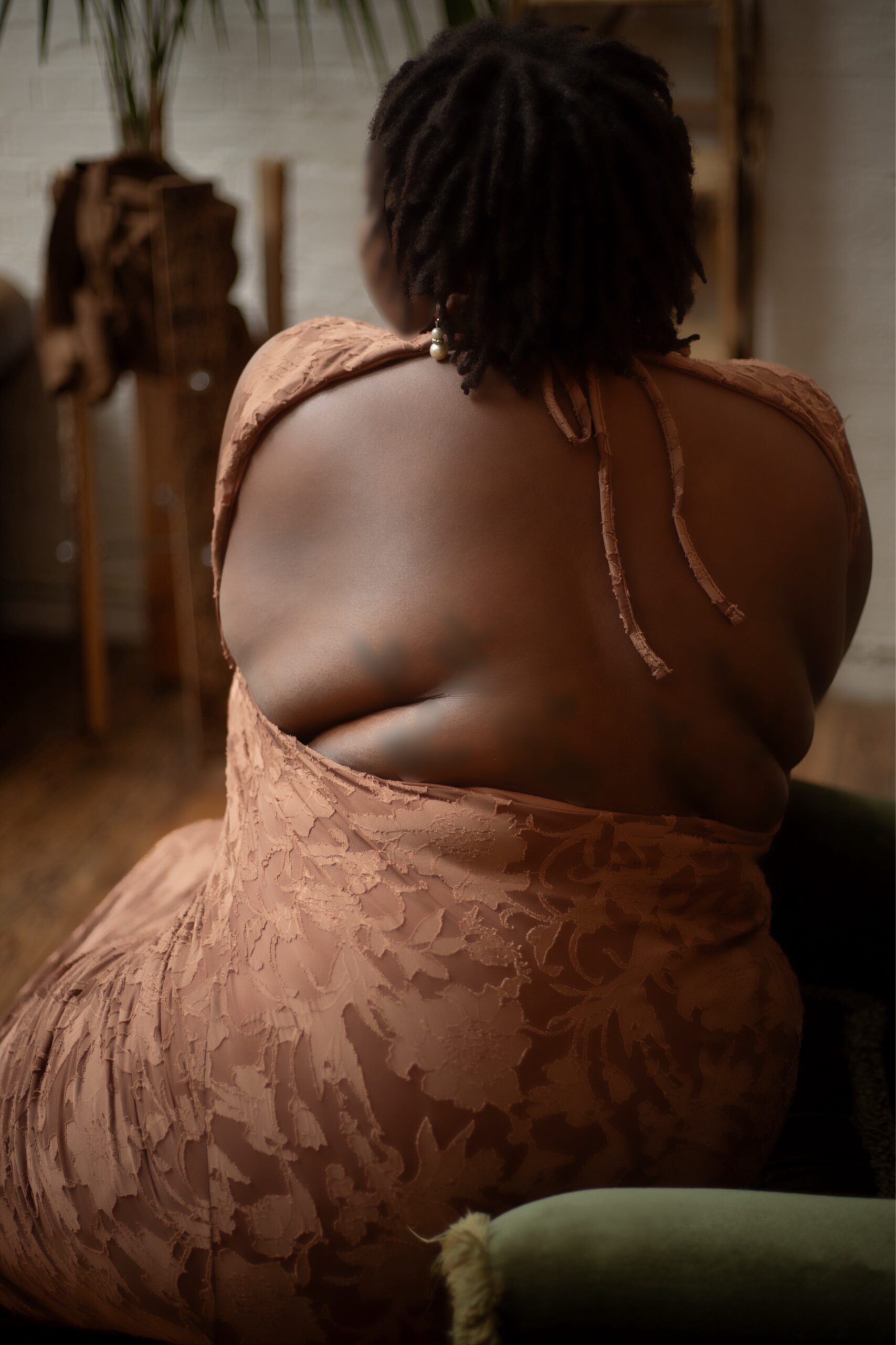 Sunny Bonheur, Black BBW escort wears a brown dress and her naked back is visible.